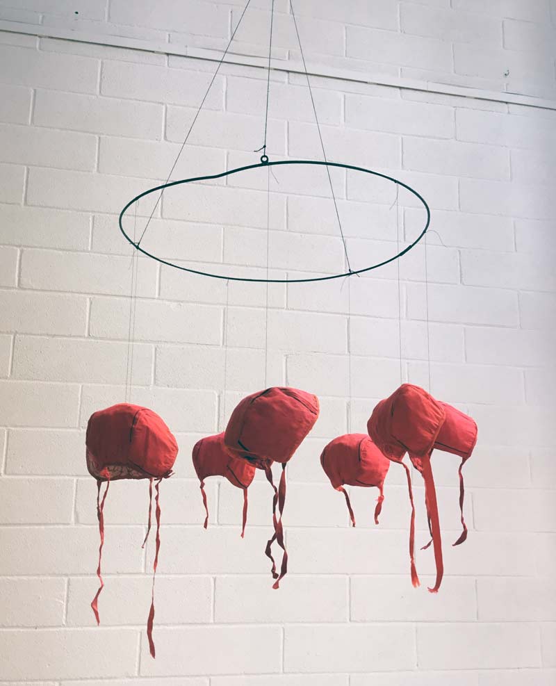 Mobilen Flickornas ringdans, de röda hättorna som blev tvättade lite för häftigt bildar blickpunkt i Karin Ferners utställning. (Foto Karin Ferner)